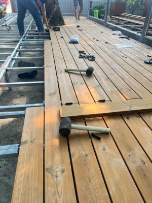 Thi công sàn gỗ thông biến tính trên hệ khung với các thanh đang được lắp nối tiếp